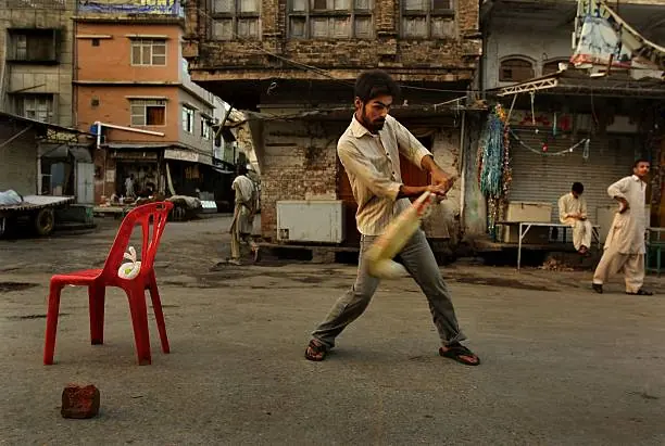 Players competing in a fast evening game of street cricket under open sky