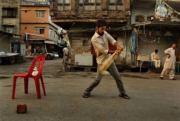 Players competing in a fast evening game of street cricket under open sky